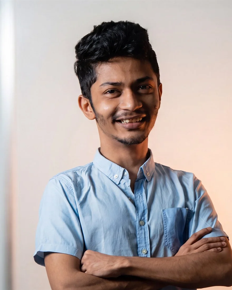Ryan Nugara, smiling, arms crossed, in a light blue shirt, against a plain wall